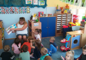 Dzieci siedzą na dywanie, nauczycielka czyta opowiadania z książki K. Makuszyńskiego „120 przygód koziołka Matołka”.